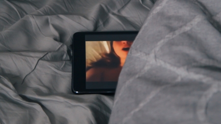 Tablette entourée d'un drap affichant une vidéo pornographique